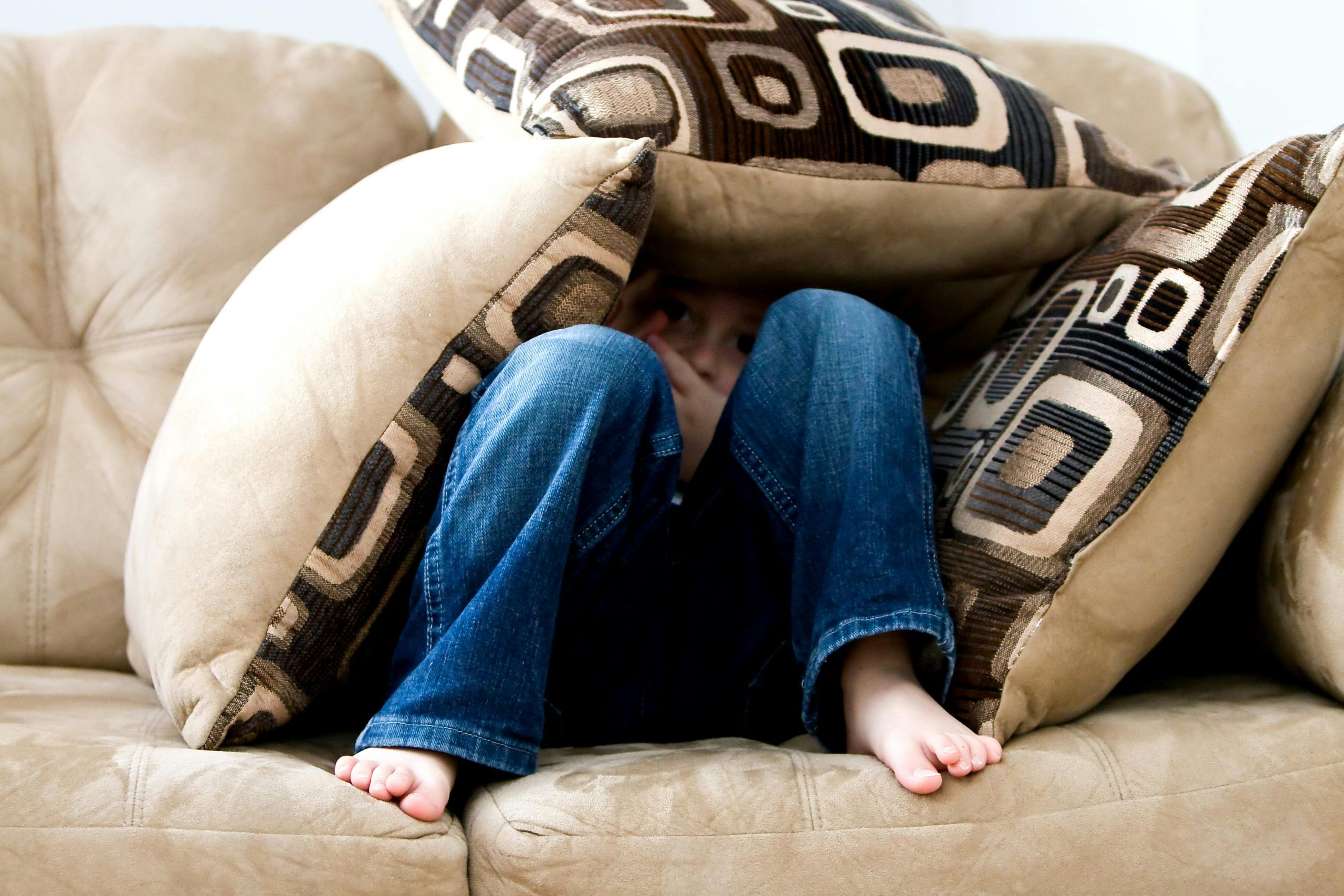 A child hiding under cushions