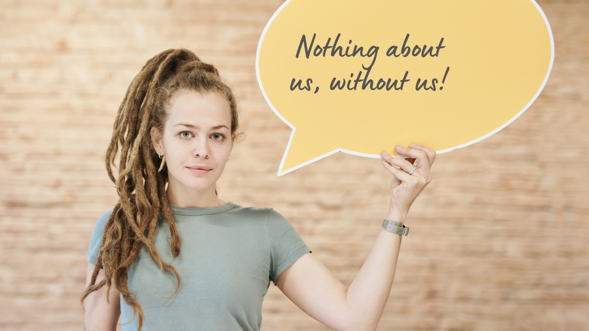 A woman with dreadlocks holds up a speech bubble which says 