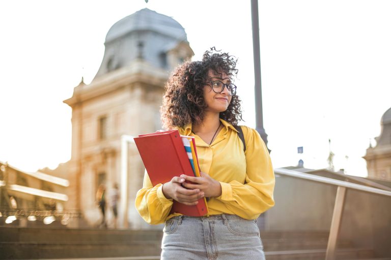 Young woman in yellow jacket holding books