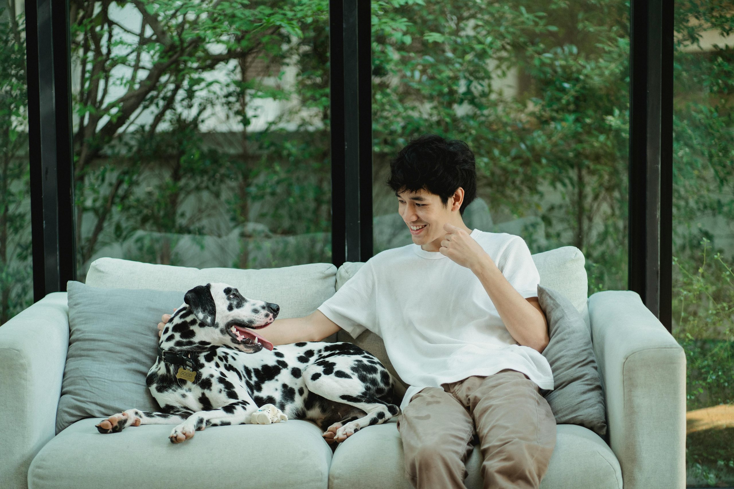 A young man sits on the couch with his dog