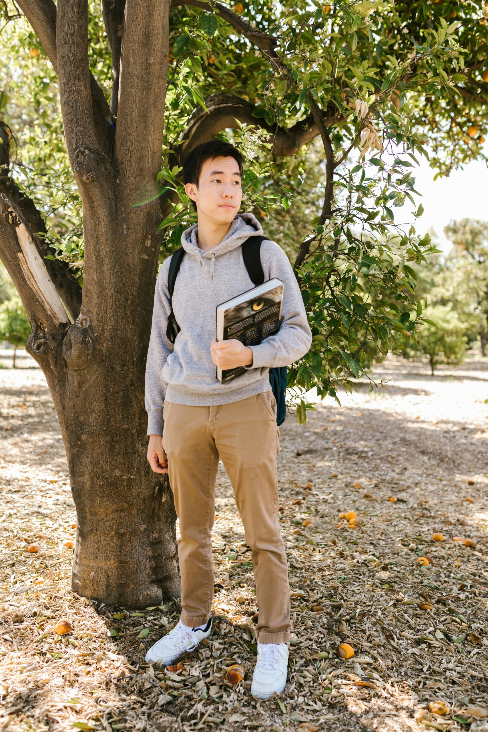 A student standing alone near a tree