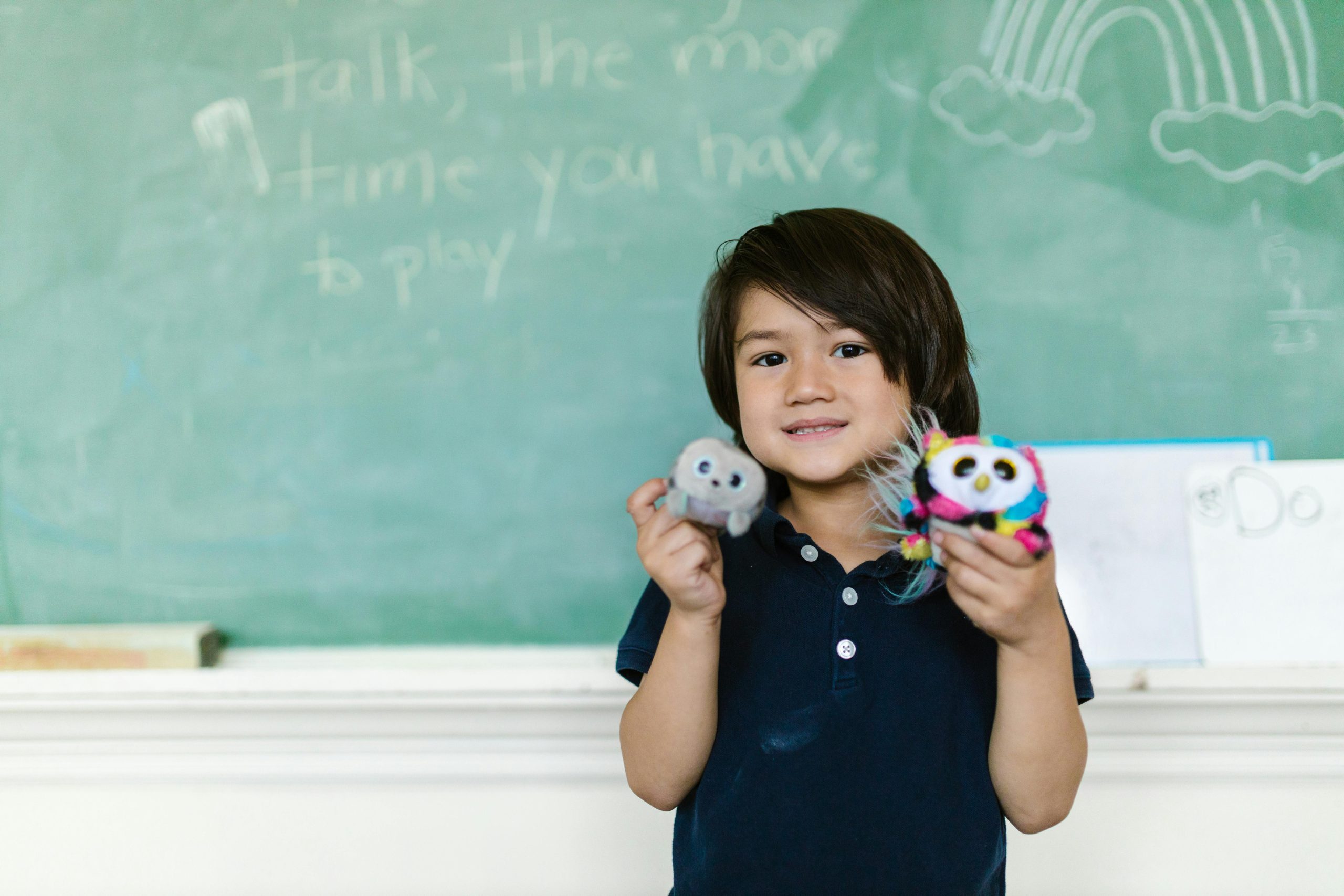 A child proudly holding their cuddly toys in a classroom