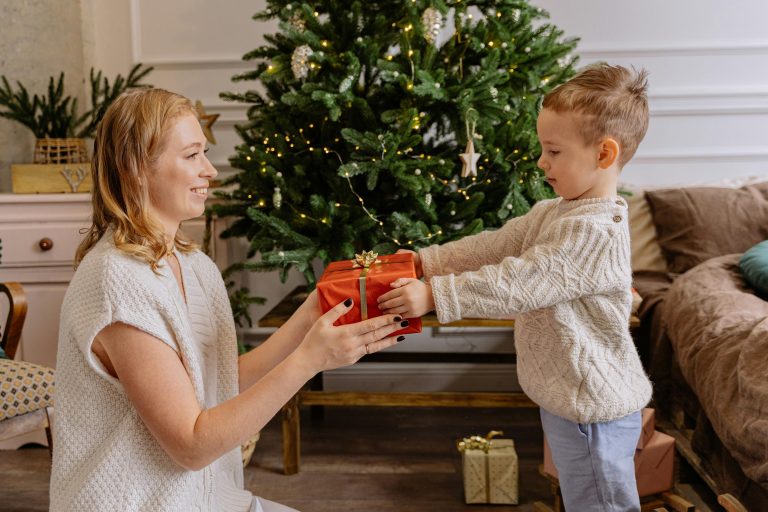 A mother hands a Christmas gift to her child