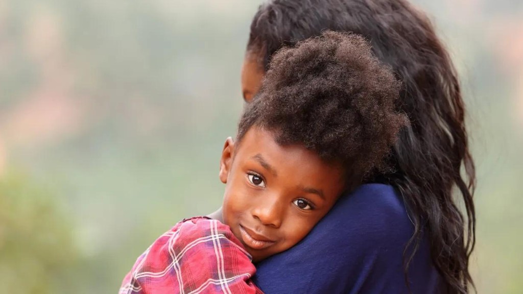 A mother comforts her child. The child is looking directly at the camera.