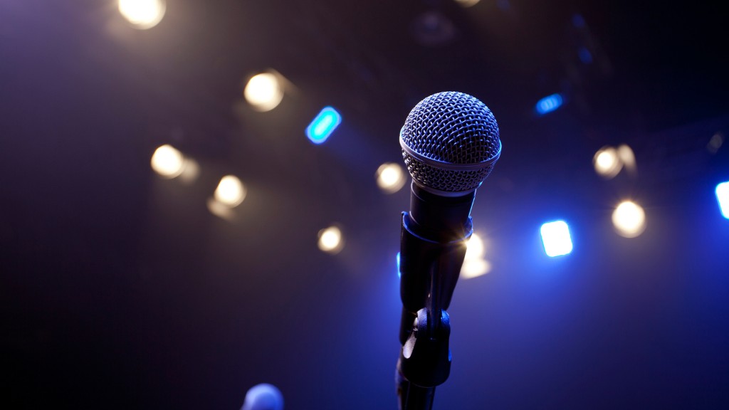 A microphone pointed at the camera, against a blue backdrop with bokeh lights.