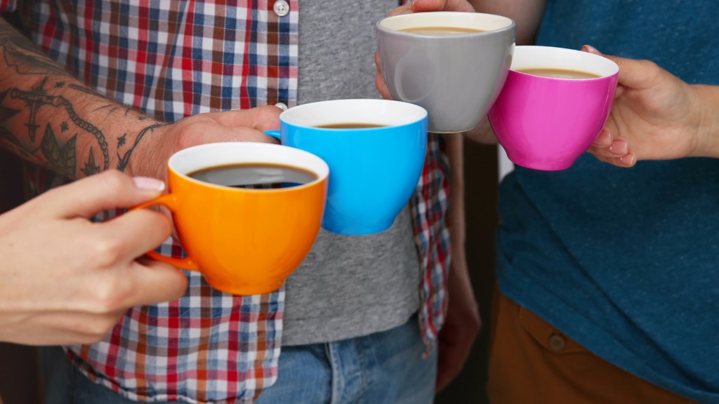 Four people cheers their coffee mugs together.