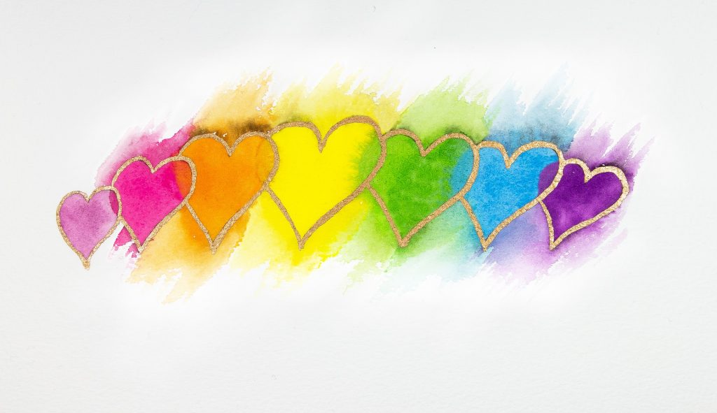 A watercolour illustration of pink, orange, yellow, green, blue and purple hearts, outlined in gold.
