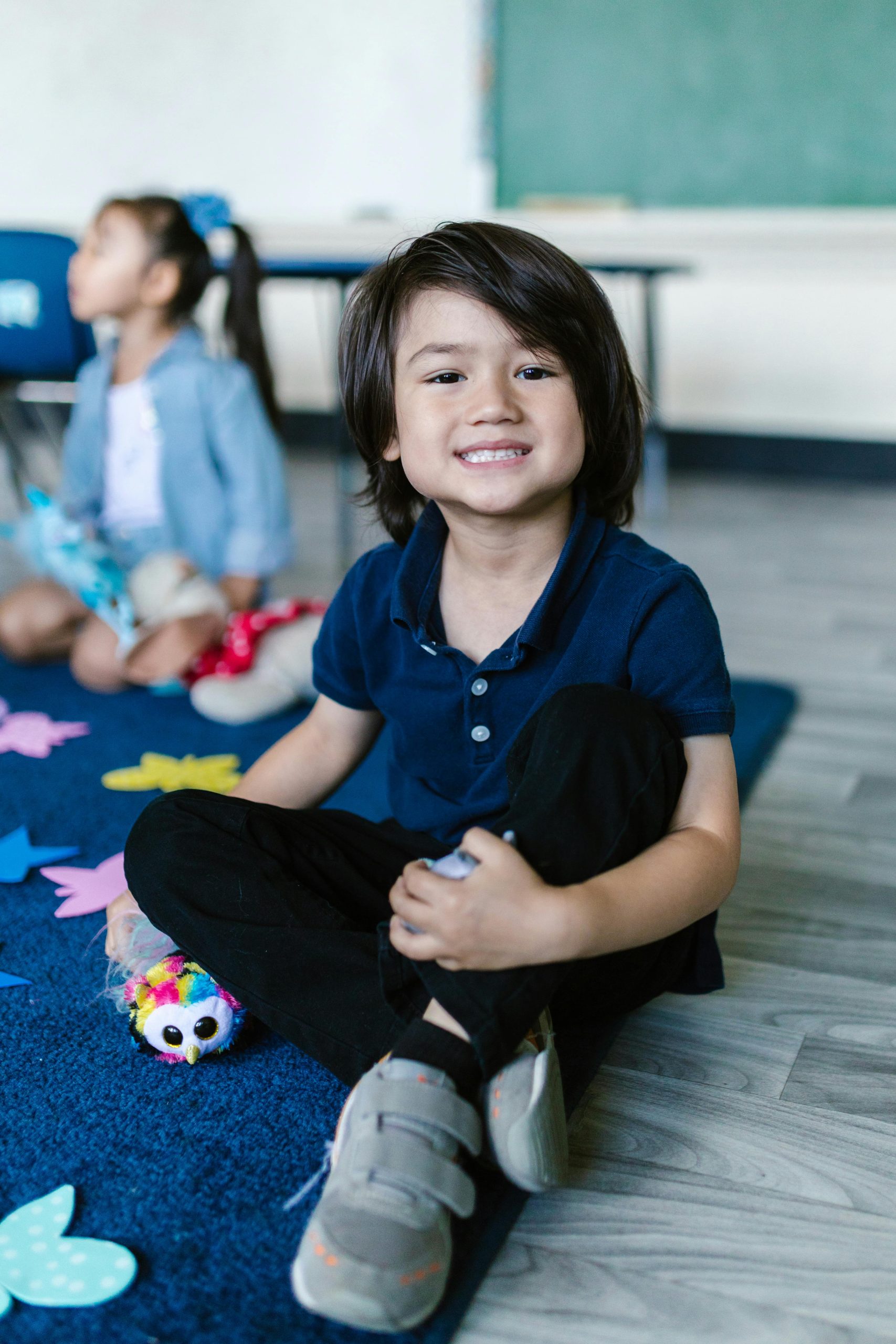 A little boy sitting on the floor at school