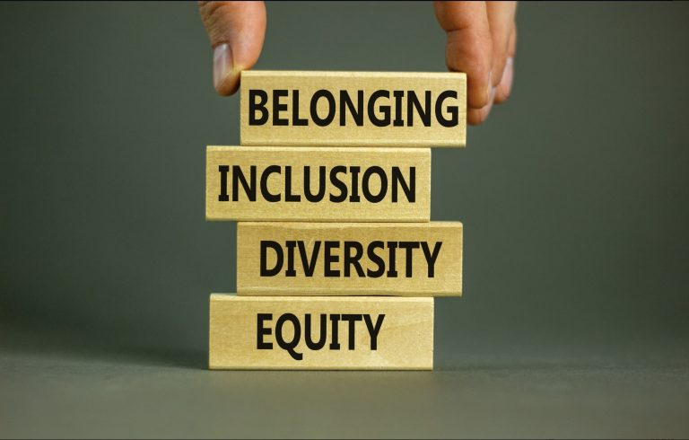 A hand stacks building blocks printed with the words equity, diversity, inclusion, and belonging.