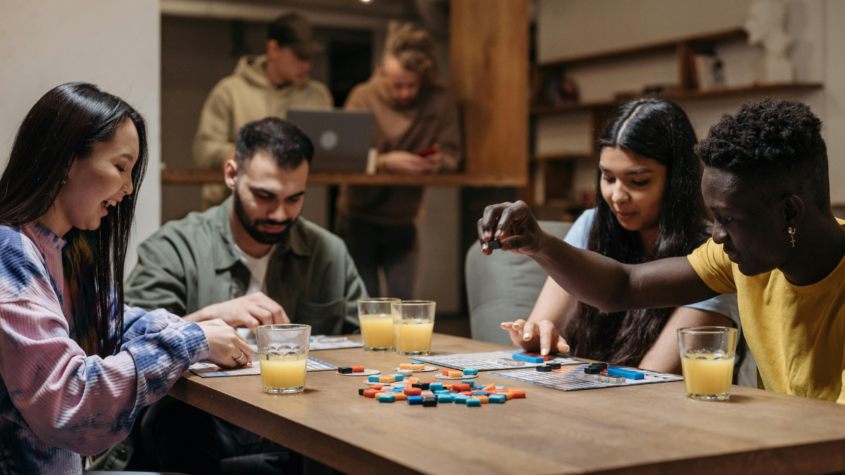 A photo of a group of young adults playing board games at a table.