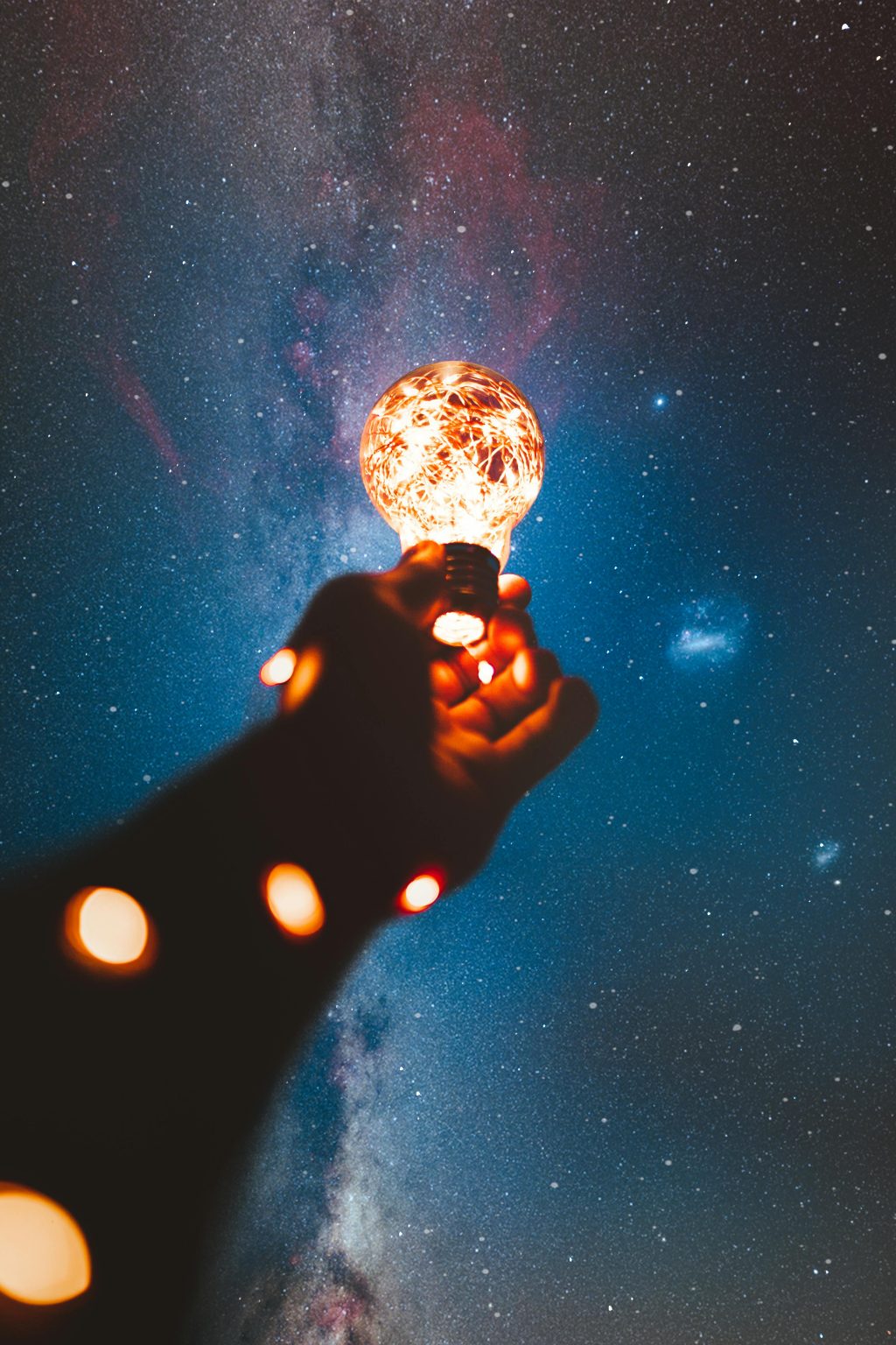 Person holding a light bulb with string lights inside